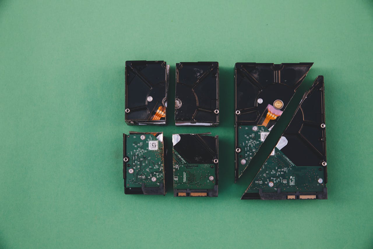 Four broken hard drives arranged on a green background, showcasing data destruction.